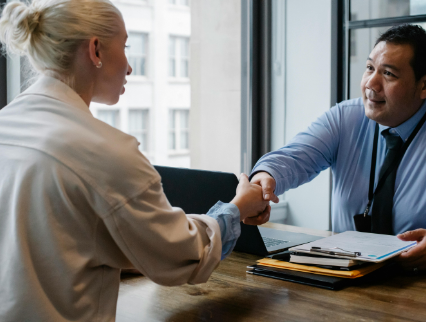 Two people shaking hands during a professional meeting at a desk.